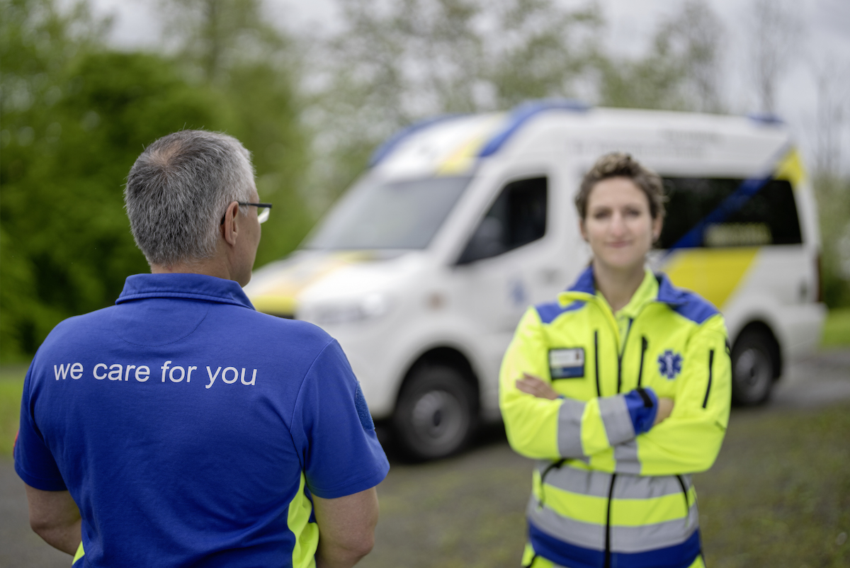 Hintergrundbild: Eine Rettungssanitäterin steht vor einer Ambulanz der Rettung St.Gallen